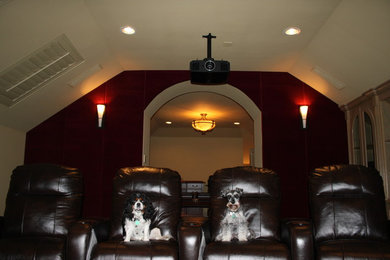 Cette photo montre une salle de cinéma chic de taille moyenne et fermée avec un mur rouge, moquette et un écran de projection.