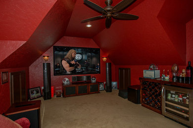 Modelo de cine en casa cerrado tradicional grande con paredes rojas, moqueta, pantalla de proyección y suelo beige