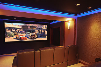 Ejemplo de cine en casa cerrado contemporáneo grande con paredes marrones, moqueta y pantalla de proyección