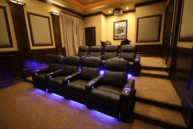 This is an example of a large rustic enclosed home cinema in Phoenix with beige walls, carpet and a projector screen.