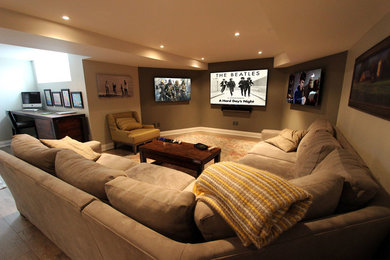 Modelo de cine en casa abierto clásico de tamaño medio con paredes beige, suelo laminado, televisor colgado en la pared y suelo marrón