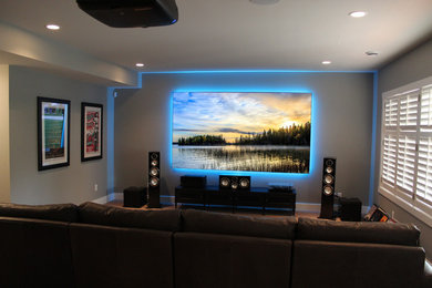 Foto de cine en casa cerrado contemporáneo de tamaño medio con paredes grises, televisor colgado en la pared, moqueta y suelo marrón