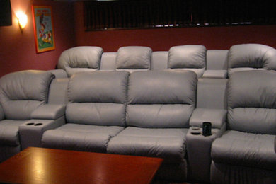 Diseño de cine en casa cerrado de tamaño medio con paredes rojas, pantalla de proyección y moqueta