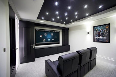 Imagen de cine en casa cerrado moderno de tamaño medio con paredes blancas, moqueta, televisor colgado en la pared y suelo gris