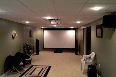 Ejemplo de cine en casa cerrado clásico de tamaño medio con paredes verdes, moqueta y pantalla de proyección