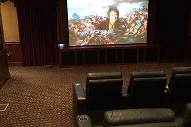 Imagen de cine en casa cerrado grande con paredes beige, moqueta y pantalla de proyección