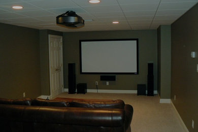 Example of a mid-sized enclosed carpeted home theater design in Philadelphia with green walls and a projector screen
