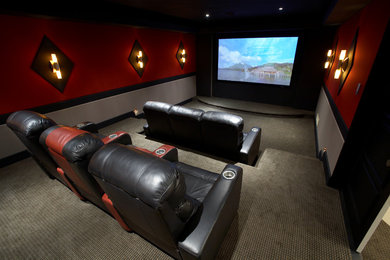 Diseño de cine en casa cerrado clásico de tamaño medio con paredes rojas, moqueta y pantalla de proyección