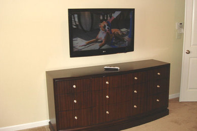 Modelo de cine en casa cerrado de tamaño medio con paredes beige, moqueta y televisor colgado en la pared