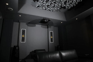 Home theater - modern carpeted home theater idea in New York with gray walls and a projector screen
