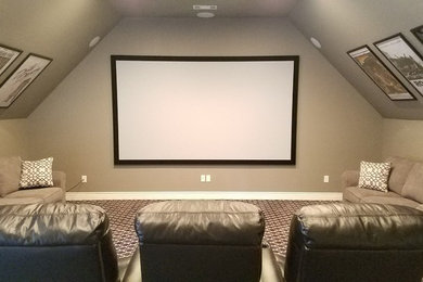 Diseño de cine en casa cerrado actual de tamaño medio con paredes beige, moqueta, pantalla de proyección y suelo multicolor