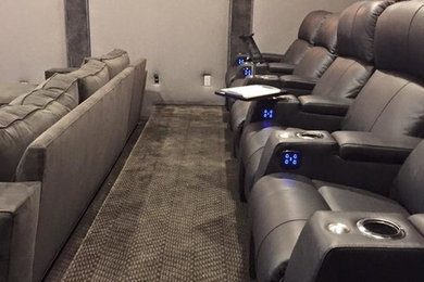 Example of a large trendy enclosed carpeted and gray floor home theater design in Los Angeles with gray walls and a wall-mounted tv