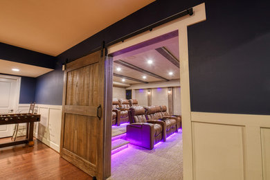 Example of a large mountain style enclosed carpeted and beige floor home theater design in DC Metro with beige walls and a projector screen