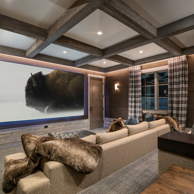 Example of a mountain style enclosed carpeted and gray floor home theater design in Other with brown walls and a projector screen