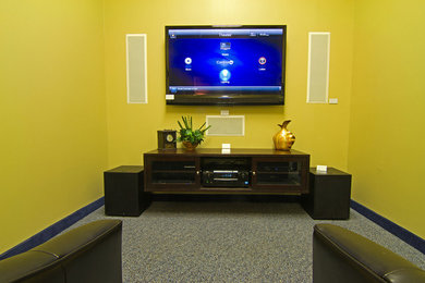 Ejemplo de cine en casa cerrado minimalista de tamaño medio con paredes amarillas, moqueta y televisor colgado en la pared