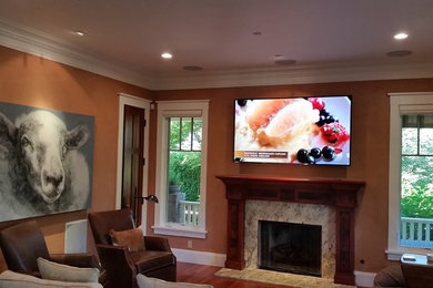 Klassisk inredning av ett mellanstort avskild hemmabio, med en väggmonterad TV, orange väggar, mörkt trägolv och brunt golv