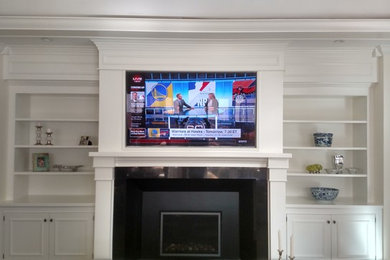 Imagen de cine en casa grande con paredes blancas y televisor colgado en la pared