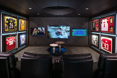 Diseño de cine en casa cerrado actual grande con paredes negras, suelo de cemento, televisor colgado en la pared y suelo gris