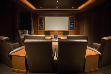 Immagine di un grande home theatre tradizionale chiuso con pareti marroni, moquette e schermo di proiezione