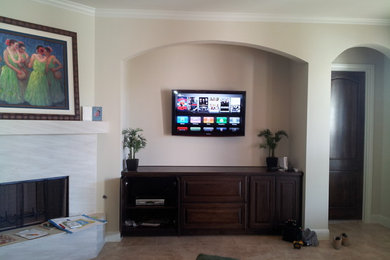 Ejemplo de cine en casa tradicional con paredes beige, suelo de baldosas de cerámica y televisor colgado en la pared