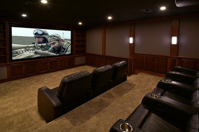 Ejemplo de cine en casa cerrado de estilo americano de tamaño medio con paredes grises, moqueta y pantalla de proyección