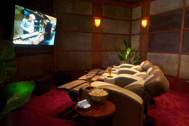 Modelo de cine en casa cerrado de estilo americano de tamaño medio con paredes multicolor, moqueta, televisor colgado en la pared y suelo rojo
