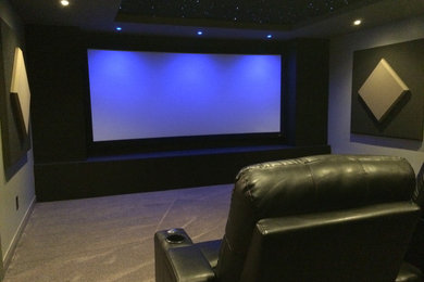 Ejemplo de cine en casa cerrado tradicional renovado de tamaño medio con paredes grises, moqueta y pantalla de proyección