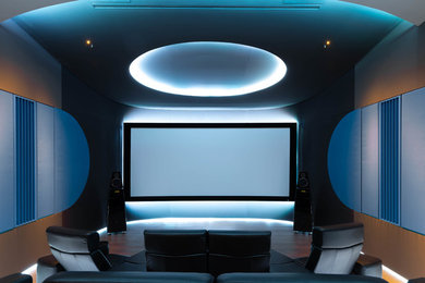 Modelo de cine en casa cerrado contemporáneo grande con paredes grises, suelo de madera en tonos medios, pantalla de proyección y suelo marrón