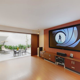 Ispirazione per un home theatre minimal di medie dimensioni e chiuso con pareti arancioni, pavimento in laminato e TV a parete