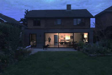 Diseño de fachada de casa negra minimalista de tamaño medio de dos plantas con revestimiento de madera, tejado plano y tejado de teja de barro