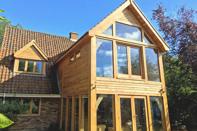 Photo of a medium sized and beige classic two floor extension in Other with wood cladding and a pitched roof.