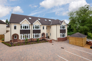 Photo of an expansive and yellow contemporary render flat in Essex with three floors, a pitched roof and a tiled roof.