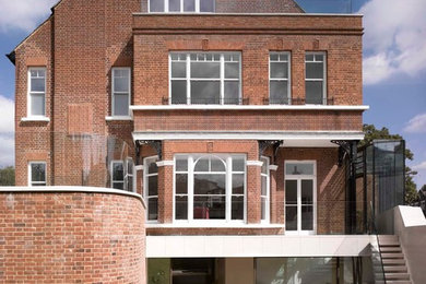 Diseño de fachada roja clásica de tres plantas con revestimiento de ladrillo y tejado a dos aguas