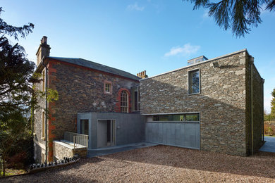 Exemple d'une façade de maison marron chic en pierre de taille moyenne et à deux étages et plus avec un toit à croupette.