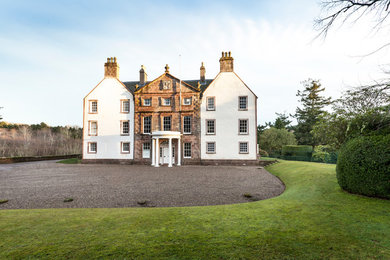 Cette photo montre une très grande façade de maison blanche chic à deux étages et plus avec un revêtement mixte et un toit à deux pans.