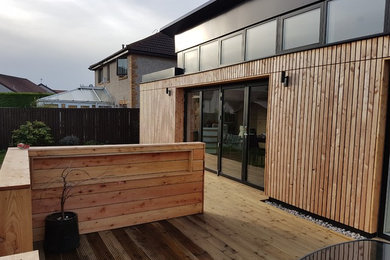 Photo of a large and black contemporary bungalow detached house in Edinburgh with wood cladding, a pitched roof and a mixed material roof.