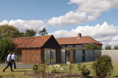 This is an example of a medium sized and gey contemporary bungalow detached house in Cambridgeshire with stone cladding, a flat roof and a green roof.