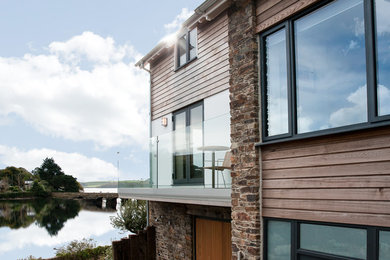 Photo of a large and white coastal detached house in Devon with three floors, wood cladding, a pitched roof and a tiled roof.