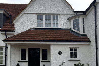 Пример оригинального дизайна: большой, двухэтажный, белый дом в классическом стиле с облицовкой из цементной штукатурки