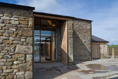 Large modern two floor house exterior in Sussex with stone cladding and a pitched roof.