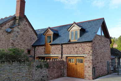 This is an example of a brown rural two floor house exterior in Other with stone cladding and a pitched roof.