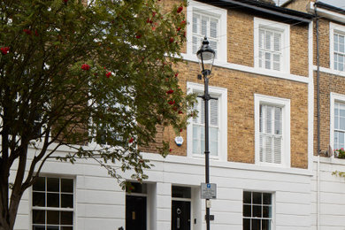 This is an example of a large and white classic brick terraced house in London with three floors, a pitched roof and a shingle roof.