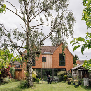 Bild på ett mellanstort funkis oranget hus, med två våningar, tegel, sadeltak och tak med takplattor