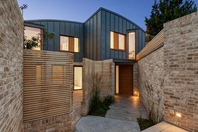 Mittelgroße, Zweistöckige Moderne Doppelhaushälfte mit Metallfassade, grauer Fassadenfarbe und Blechdach in London