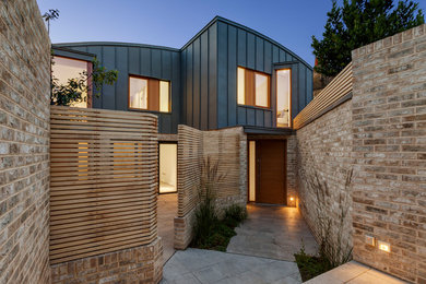 Idée de décoration pour une façade de maison mitoyenne métallique et grise minimaliste de taille moyenne et à un étage avec un toit en métal.