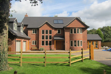 Exempel på ett stort klassiskt rött hus, med tre eller fler plan, tegel, sadeltak och tak med takplattor
