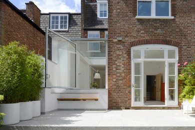 На фото: дом среднего размера в современном стиле с облицовкой из цементной штукатурки и плоской крышей с