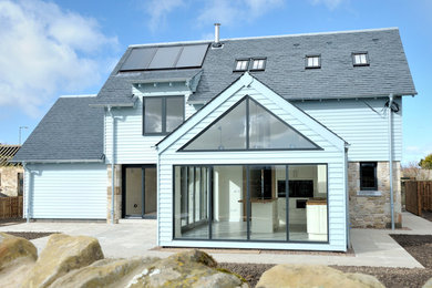 Photo of a medium sized and blue farmhouse two floor house exterior in Edinburgh with wood cladding and a pitched roof.