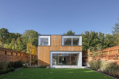 Design ideas for a large contemporary house exterior in London with three floors and wood cladding.