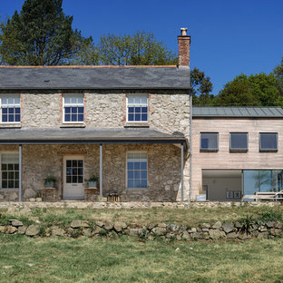 This is an example of a large and beige farmhouse two floor detached house in Devon with stone cladding and a pitched roof.